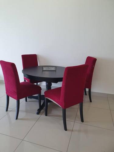 three red chairs around a black table with a piano at Southbay Seaview Condo A10 #10minQueensbay #15minSPICE in Bayan Lepas