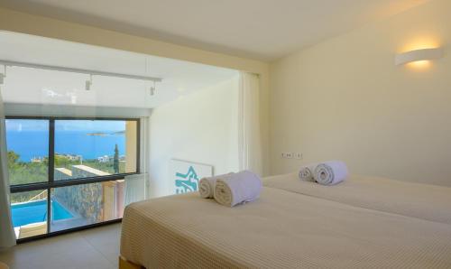 a bedroom with two beds and a large window at Mirabella Hills in Agios Nikolaos