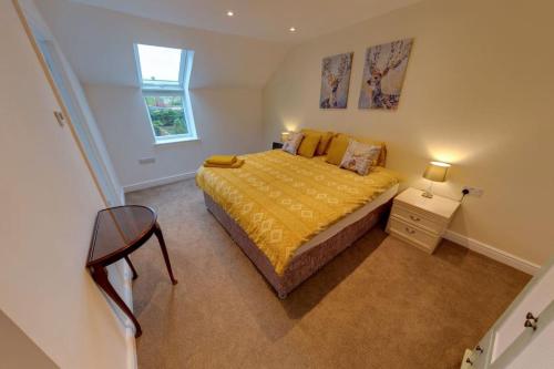 1 dormitorio con 1 cama con colcha amarilla en The Coach House, en Westoe