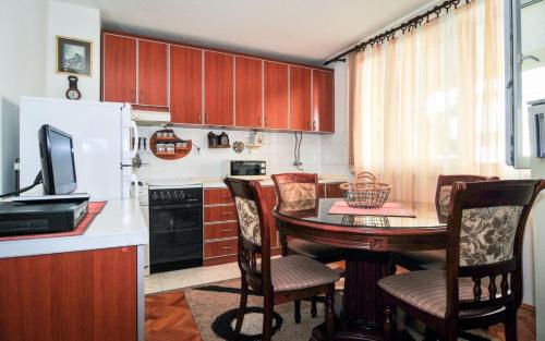 a kitchen with a table with chairs and a refrigerator at Apartmani Andjelka in Tivat