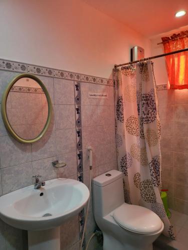 een badkamer met een toilet, een wastafel en een spiegel bij Rooms R Us - Voyagers Palace in Puerto Princesa City