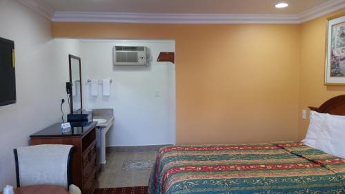 a hotel room with a bed and a sink at Kona Inn Motel Anaheim in Anaheim