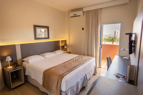 um quarto de hotel com uma cama e uma varanda em JR Hotel Marilia em Marília