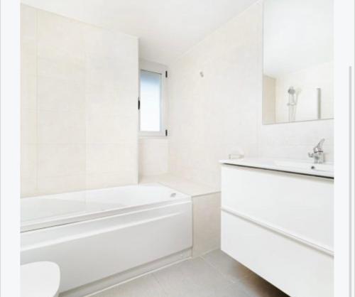 a white bathroom with a tub and a sink at Magnifique Apartament Valencia in Valencia