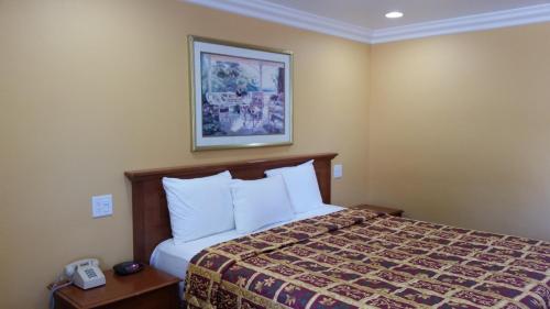 a hotel room with a bed and a picture on the wall at Kona Inn Motel Anaheim in Anaheim