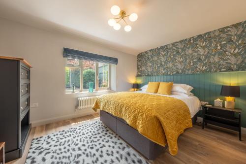 a bedroom with a bed with a yellow blanket and a window at Castle Bungalow in Thornham