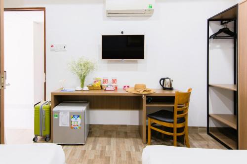 a room with a desk with a tv on a wall at Arise Seaside Hotel in Nha Trang