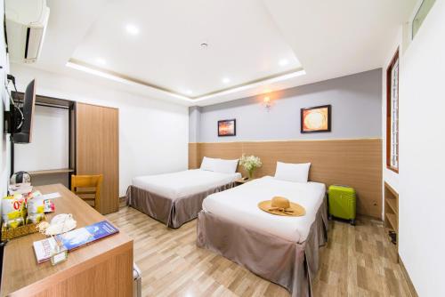 a hotel room with two beds and a table at Arise Seaside Hotel in Nha Trang