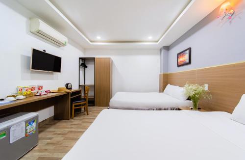 a hotel room with two beds and a desk at Arise Seaside Hotel in Nha Trang