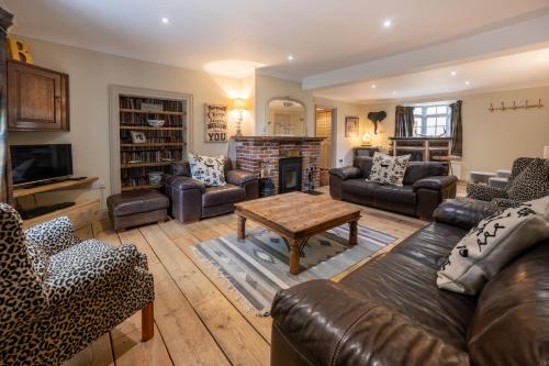 a living room with leather furniture and a fireplace at The Old Manor House in Brancaster