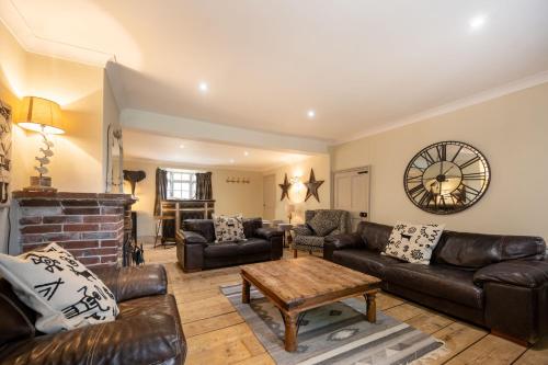 a living room with leather furniture and a fireplace at The Old Manor House in Brancaster