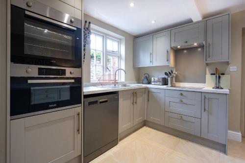 a kitchen with white cabinets and stainless steel appliances at The Old Manor House in Brancaster