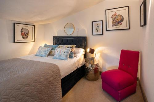 a bedroom with a bed and a red chair at The Old Manor House in Brancaster