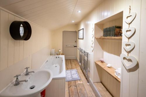 uma casa de banho com um lavatório e uma banheira com corações na parede em The Old Manor House em Brancaster