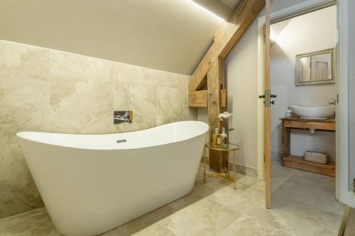 een badkamer met een groot wit bad en een wastafel bij Fallow Folly in Little Massingham