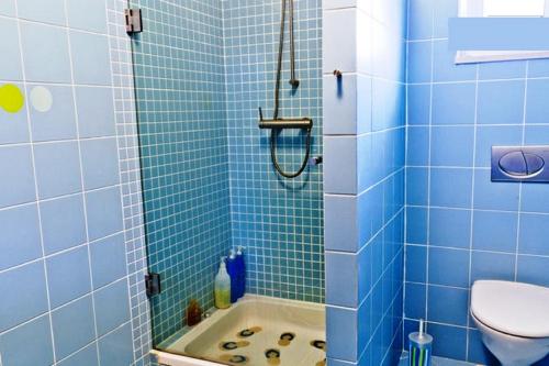 a blue tiled bathroom with a tub and a toilet at Coloured Studio in Faro