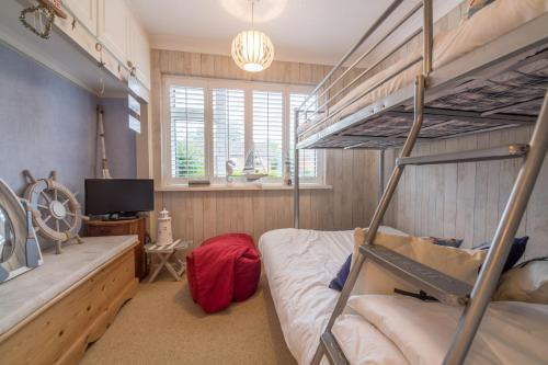 a bedroom with two bunk beds and a tv at Whitehaven in Brancaster