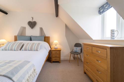 um quarto com uma cama, uma cómoda e uma janela em Twitchers Cottage em Titchwell