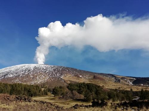 a snow covered mountain with a cloud of smoke at PetraSicula Apartment in Acitrezza