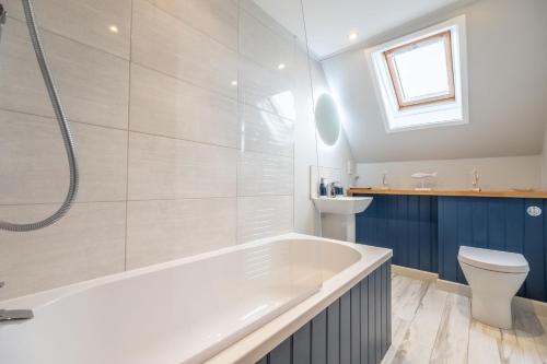 a bathroom with a tub and a toilet and a sink at Cornloft Cottage in South Creake