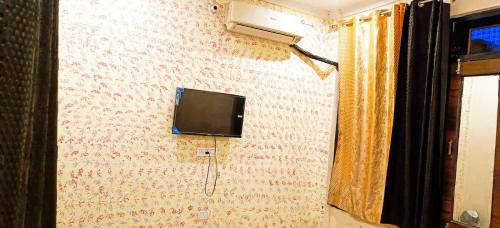 OYO Dream Guest House في Rāmpura: تلفزيون على جدار الغرفة
