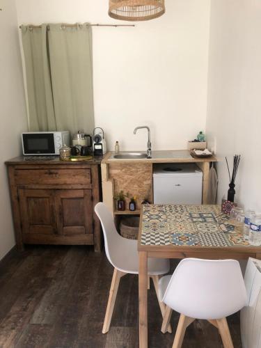 eine Küche mit einem Tisch, Stühlen und einem Waschbecken in der Unterkunft Le paradis des ouches in Aubigny