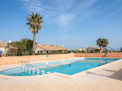 a large swimming pool with a palm tree in the background at Appartement Loupian, 2 pièces, 4 personnes - FR-1-604-9 in Loupian