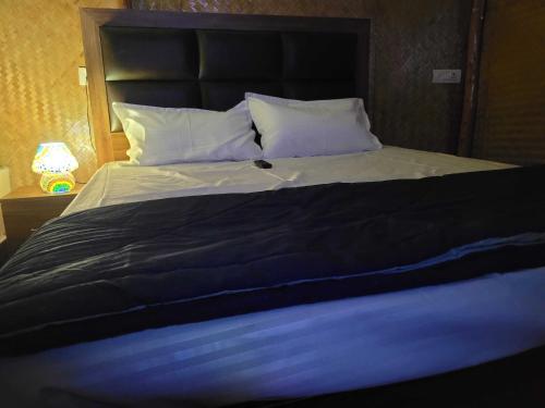 a large bed with a black blanket and white pillows at Royal Tree Cafe And Resort in Dehradun