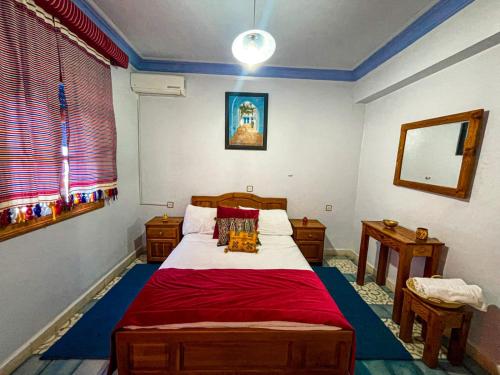 a bedroom with a large bed with a red blanket at Hôtel Al Kalaa in Chefchaouen