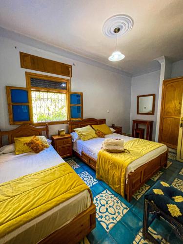 a bedroom with two beds and a window at Hôtel Al Kalaa in Chefchaouen