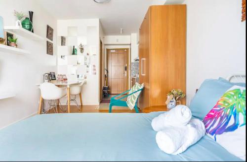 a bedroom with a blue bed and a desk at Staycation in Manila (2 min. walk to Robinson's) in Manila