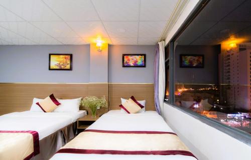 two beds in a room with a window at Arise Seaside Hotel in Nha Trang