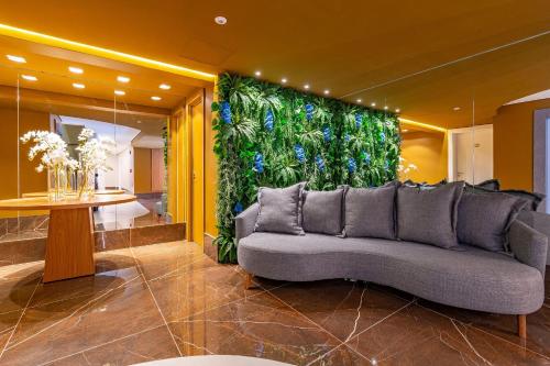 een woonkamer met een bank voor een groene muur bij Rosa Edifício Reservas das Orquídeas in Gramado