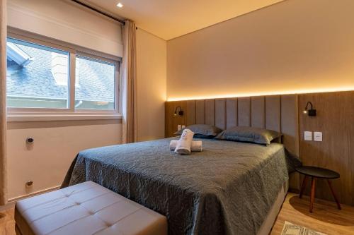 een slaapkamer met een bed en een raam bij Rosa Edifício Reservas das Orquídeas in Gramado