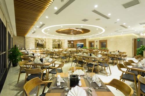 a restaurant with tables and chairs in a room at Pavilion Hotel Da Nang in Da Nang