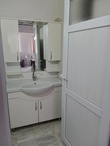 a white bathroom with a sink and a mirror at Rainford aprt in Denizli