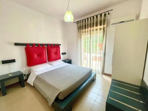 a bedroom with a bed with red pillows and a window at Aparthotel Isabella in Sciacca