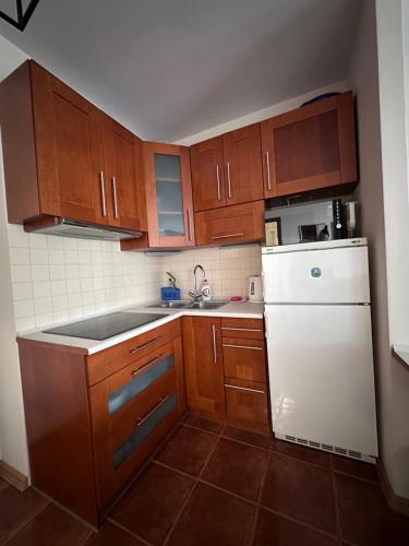 cocina con armarios de madera y nevera blanca en Apartament Międzyzdroje z widokiem na morze, en Międzyzdroje