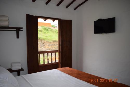 a bedroom with a bed and a window with a television at Casona CHARA in Barichara