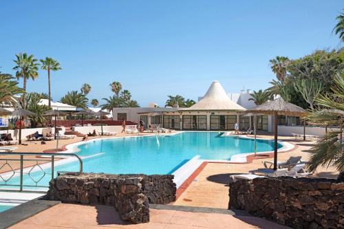 a pool at a resort with people sitting around it at Al Sole Studios residence Playa Roca in Costa Teguise
