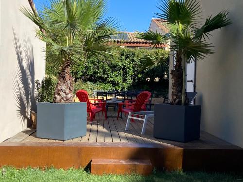 une terrasse avec des palmiers, une table et des chaises dans l'établissement Chez Céline, à Saumane-de-Vaucluse