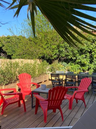 une terrasse avec des chaises rouges, une table et des chaises dans l'établissement Chez Céline, à Saumane-de-Vaucluse