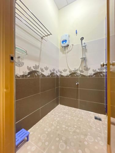 La salle de bains est pourvue d'une douche avec du carrelage brun et blanc. dans l'établissement BE TONG Residences, à Cần Thơ