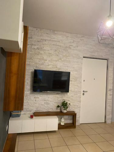 uma sala de estar com televisão numa parede de tijolos em Lovely Home em Avezzano
