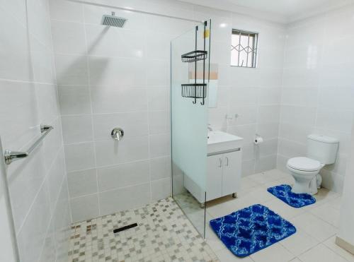 a white bathroom with a shower and a toilet at Golden Candle Guest House in Roodepoort