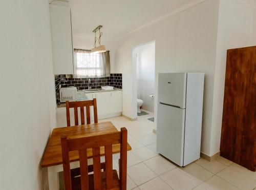 a kitchen with a table and a white refrigerator at Golden Candle Guest House in Roodepoort