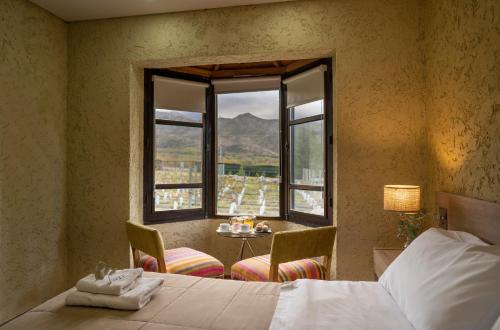 a bedroom with a bed and a table and windows at Ayres de Uco Lodge & Wine Lovers in Los Árboles