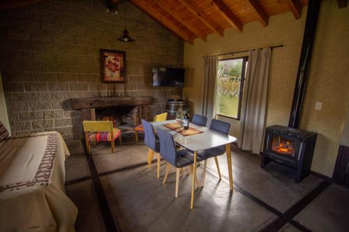 een kamer met een tafel en stoelen en een open haard bij Ayres de Uco Lodge & Wine Lovers in Los Árboles