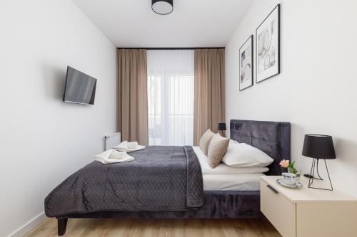 a white bedroom with a bed and a window at Apartamenty Sunset Resort by Renters in Grzybowo