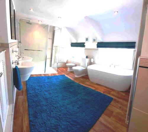 a bathroom with a blue rug and a tub and sink at Pretty Neyland Cottage central to all attractions in Milford Haven